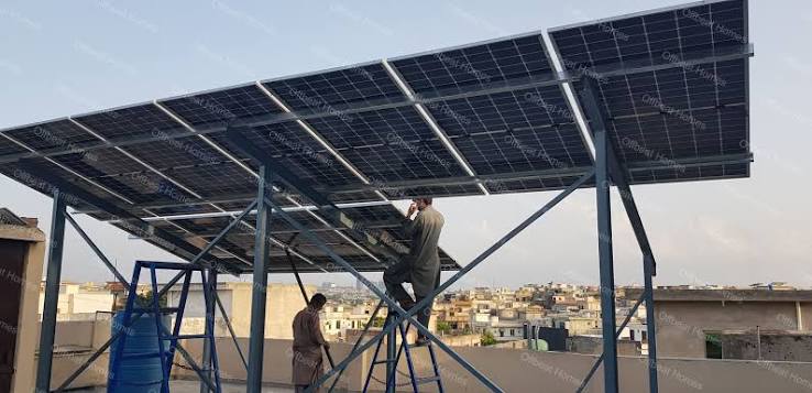 Elevated rooftop solar panel structure with installers working beneath it
